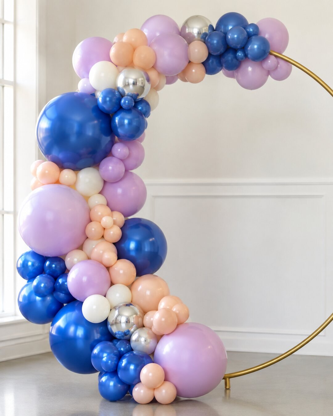 Close detail of cobalt orchid peach ivory and chrome silver balloons wrapped around a gold ring