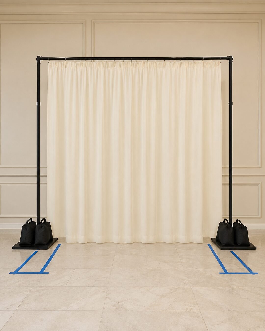 Freestanding ten foot wedding backdrop frame with an ivory base curtain four sandbags and taped floor marks