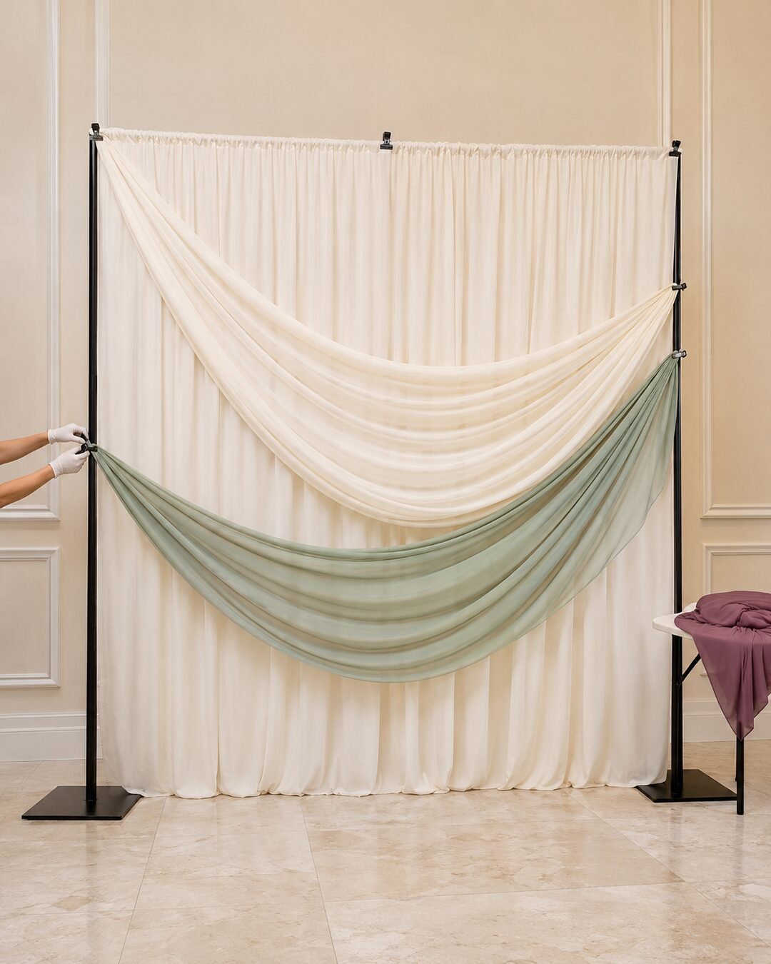 Halfway sculptural draped wedding backdrop with ivory and sage fabric waves being clamped to a freestanding frame