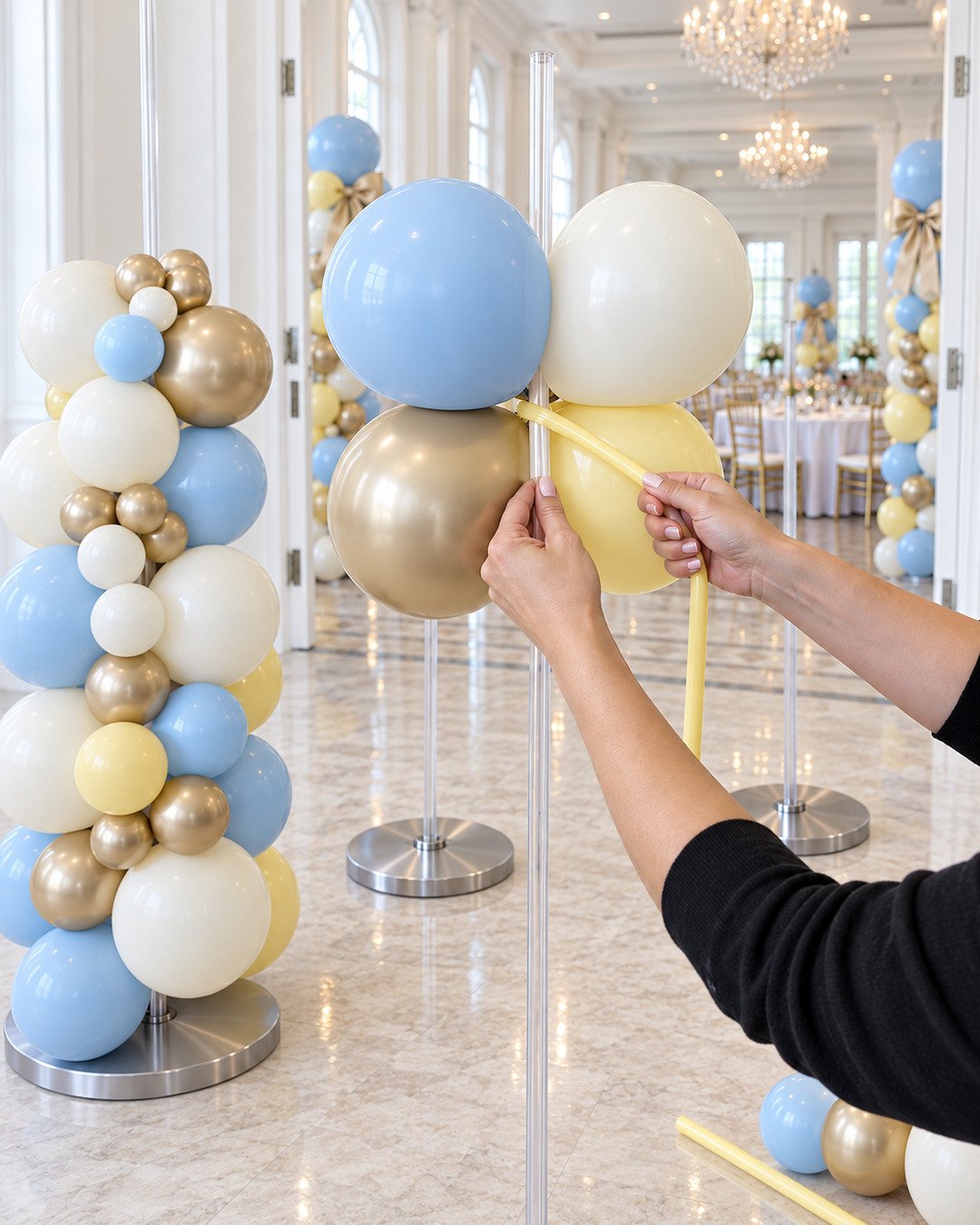 Decorator attaching a powder-blue, butter-yellow, ivory and champagne-gold balloon quad securely to a clear pole